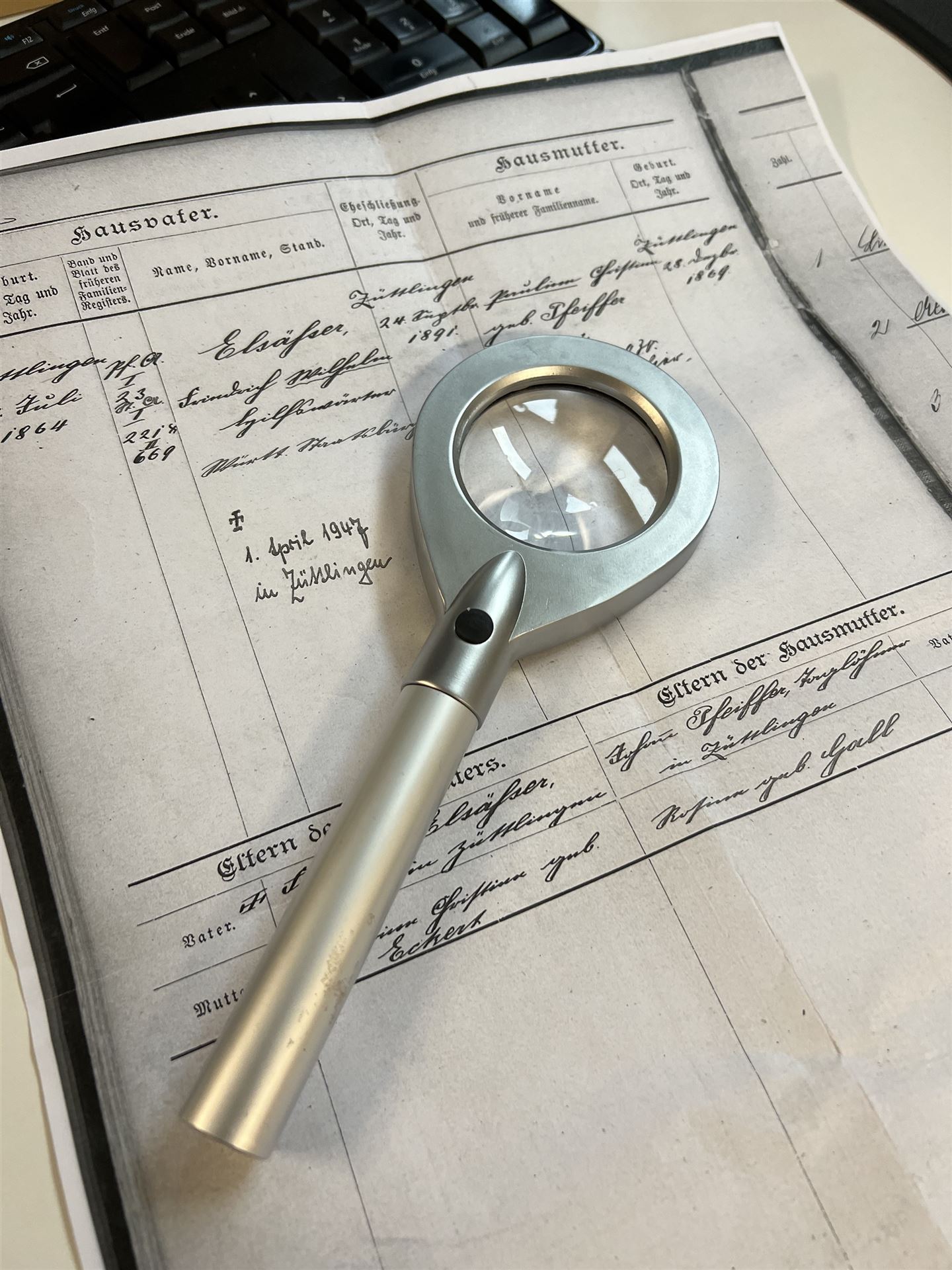 Arbeitsplatz zur Entzifferung eines alten Familienregisters mit Lupe